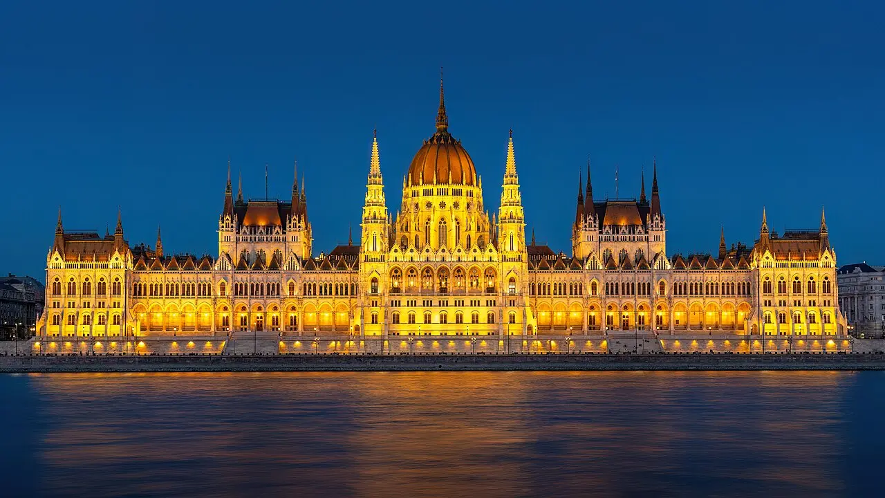 Il Parlamento ungherese illuminato sul Danubio al crepuscolo.